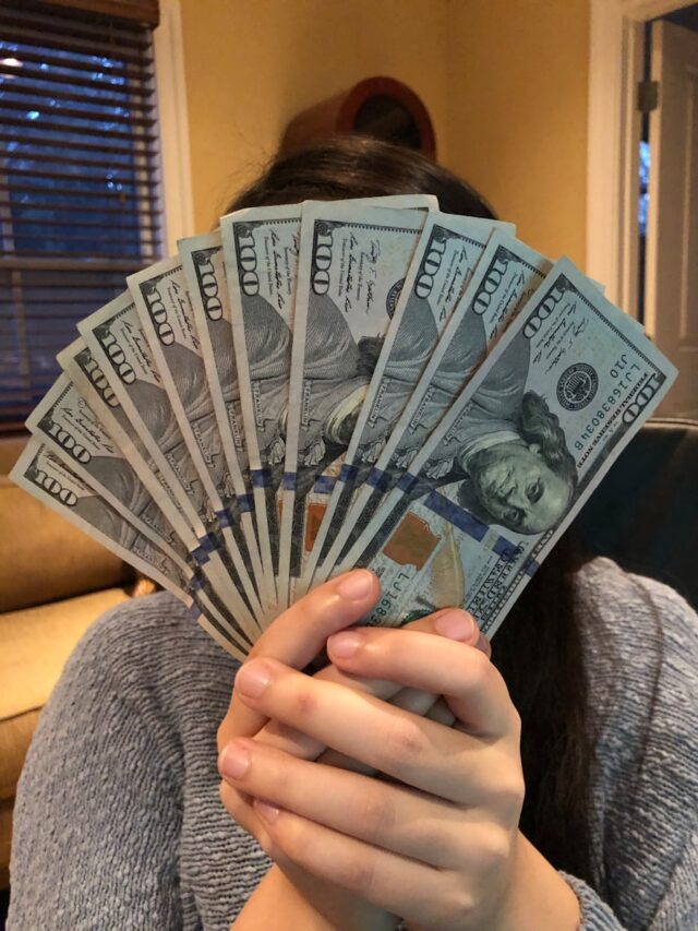 person holding fan of us dollar bill